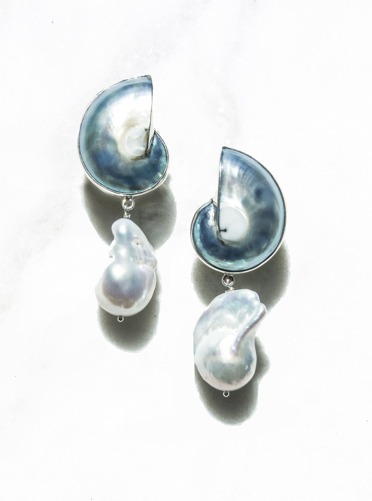 A pair of 925 Silver Encased Blue Nautilus Shell Drop Earrings with large baroque pearls against a white background | Lily Frank Jewelry