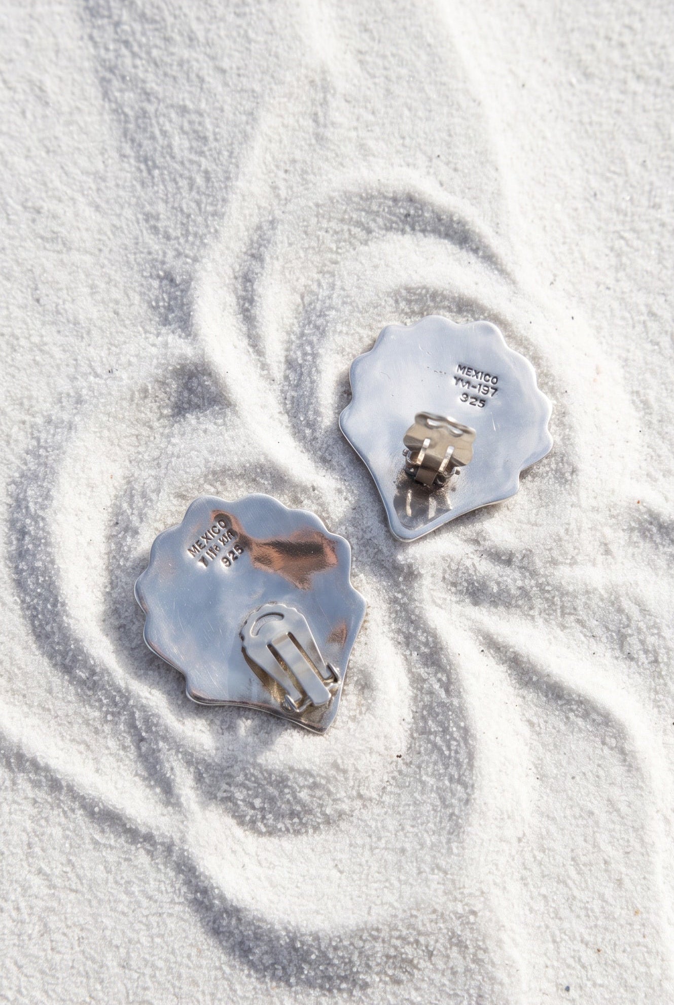 Vintage 925 silver large shell earrings shown face down to reveal the hallmark and clip on closures on a sandy background | Lily Frank Jewelry 