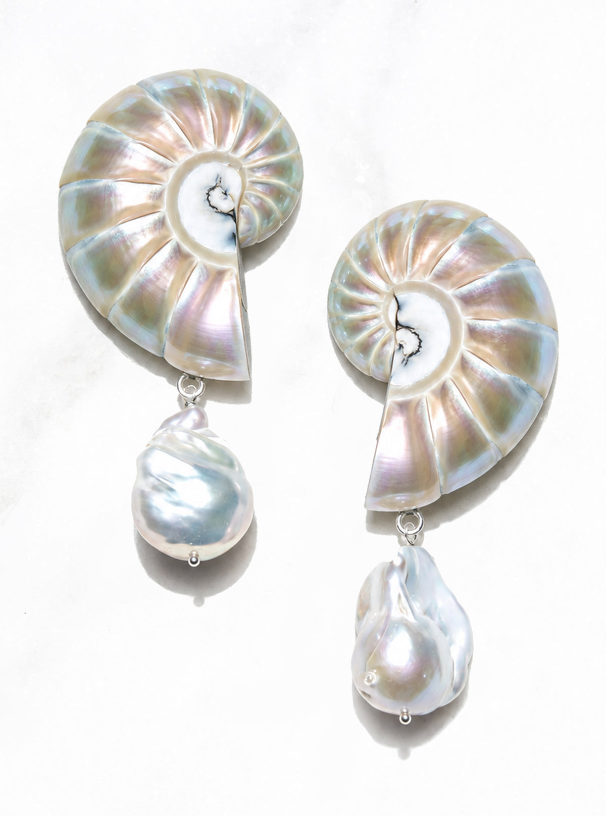 Pair of large pearl nautilus shell drop earrings with tips facing down and baroque pearls on a white background.