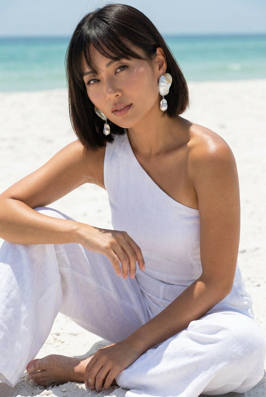 Woman wearing large pearl nautilus drop earrings in lavender linen on beach — Lily Frank Jewelry