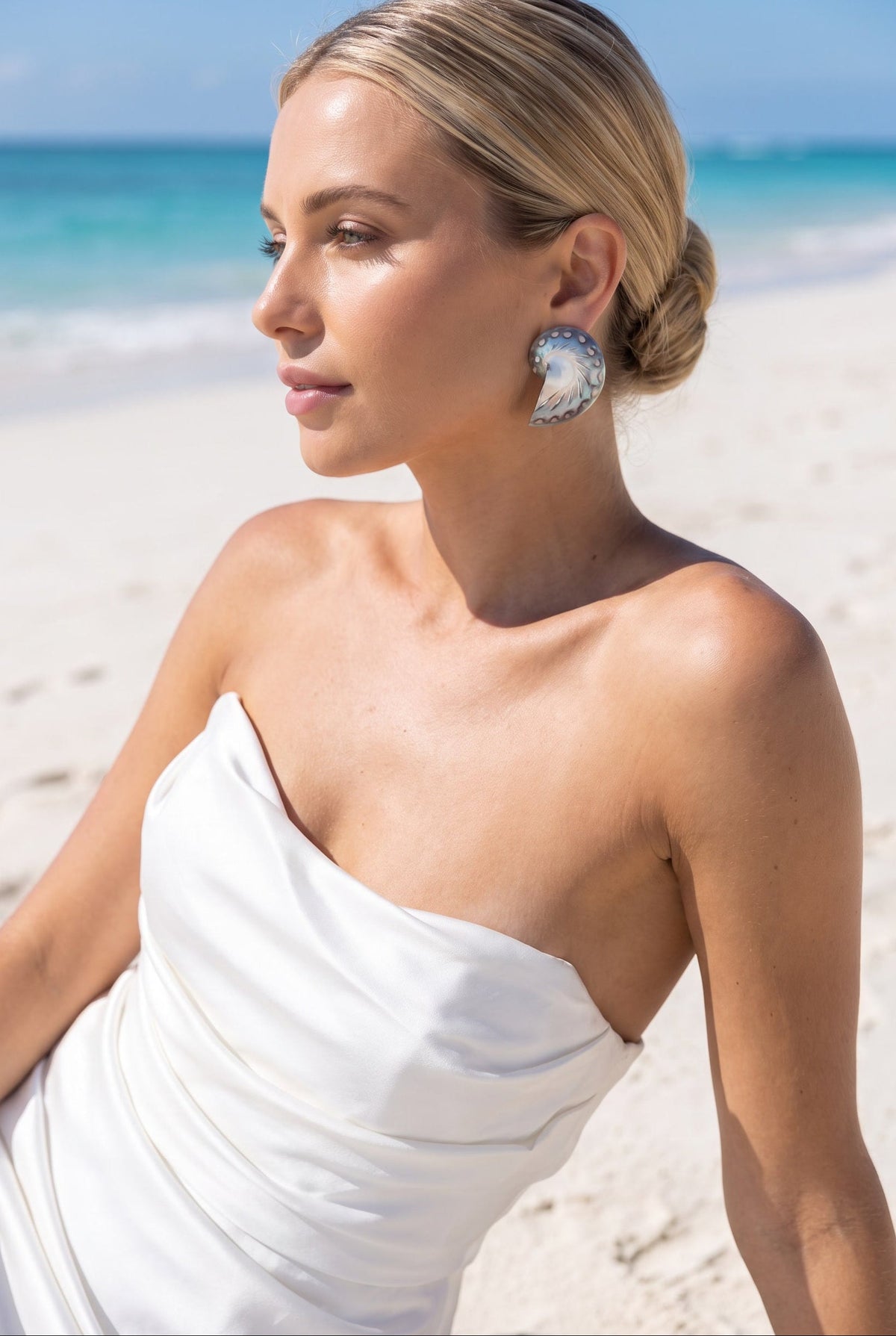 Medium Jaguar Nautilus Shell Earrings worn with a white strapless dress, shown in profile on the beach | Lily Frank Jewelry