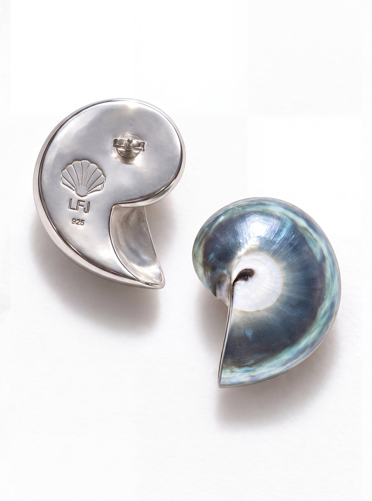 A pair of mini blue nautilus shell earrings, one in polished silver-tone metal with a scallop shell engraving and the other in iridescent blue-green mother-of-pearl, displayed on a clean white background.
