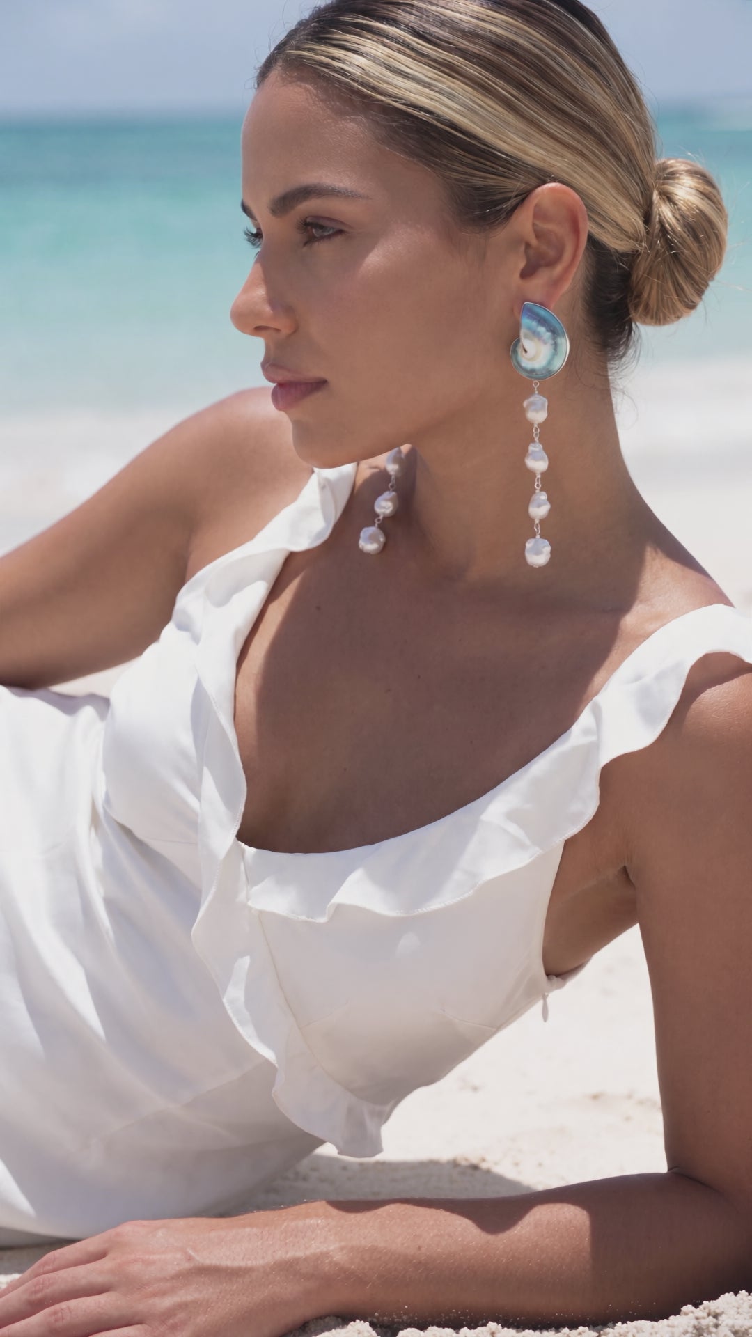 Video of a woman gently touching 925 silver encased blue nautilus shell cascade earrings with baroque pearls on a beach | Lily Frank Jewelry
