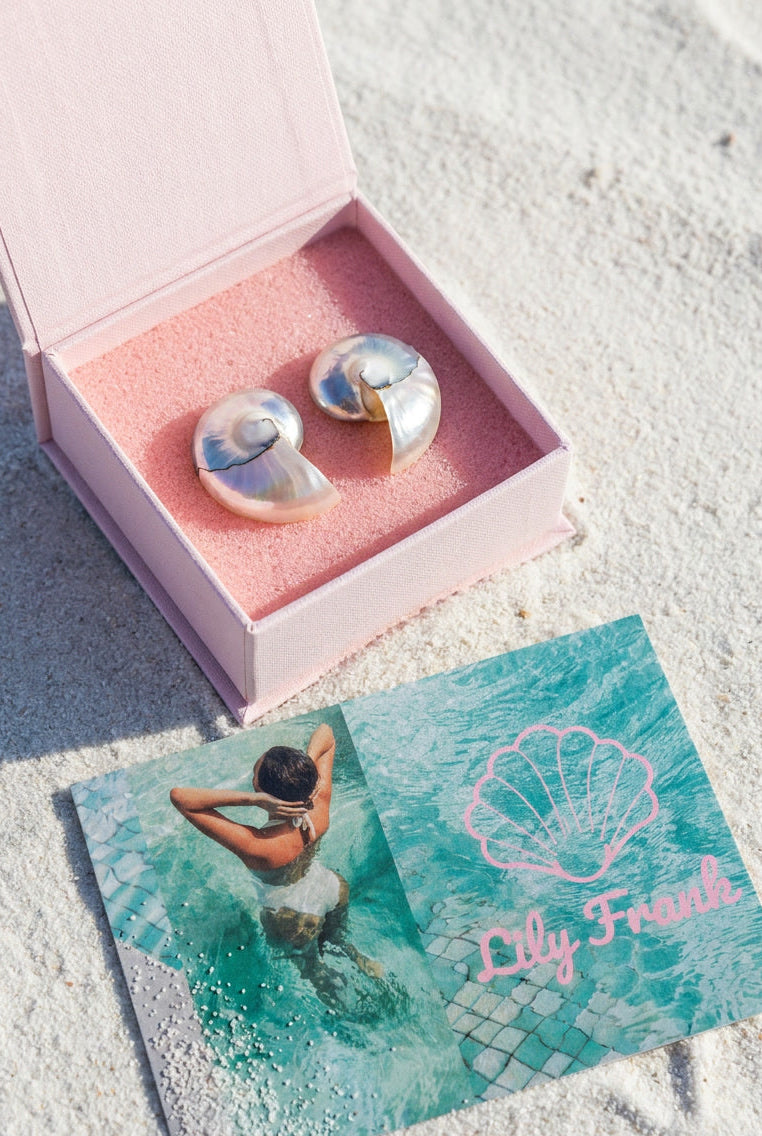 Two-toned nautilus shell earrings in pink gift box with Lily Frank branding card on sand — Lily Frank Jewelry