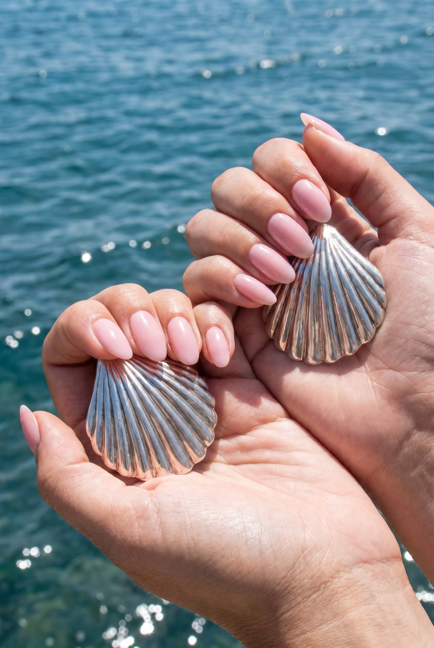 a pair vintage oversized 925 silver shell earrings held by hands with a blurred blue water background | Lily Frank Jewelry 