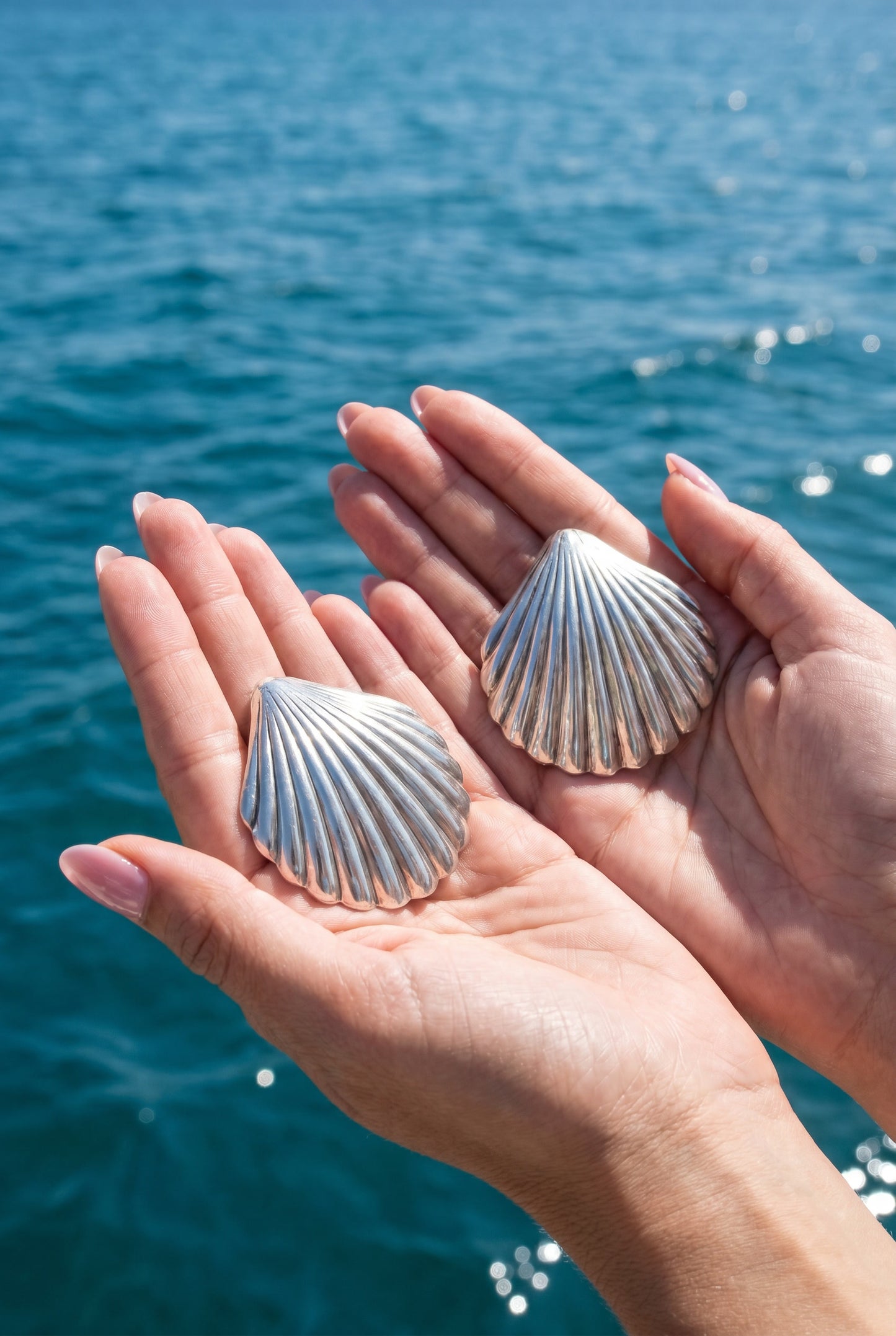 a pair vintage oversized 925 silver shell earrings held in hands against a blue ocean background | Lily Frank Jewelry 